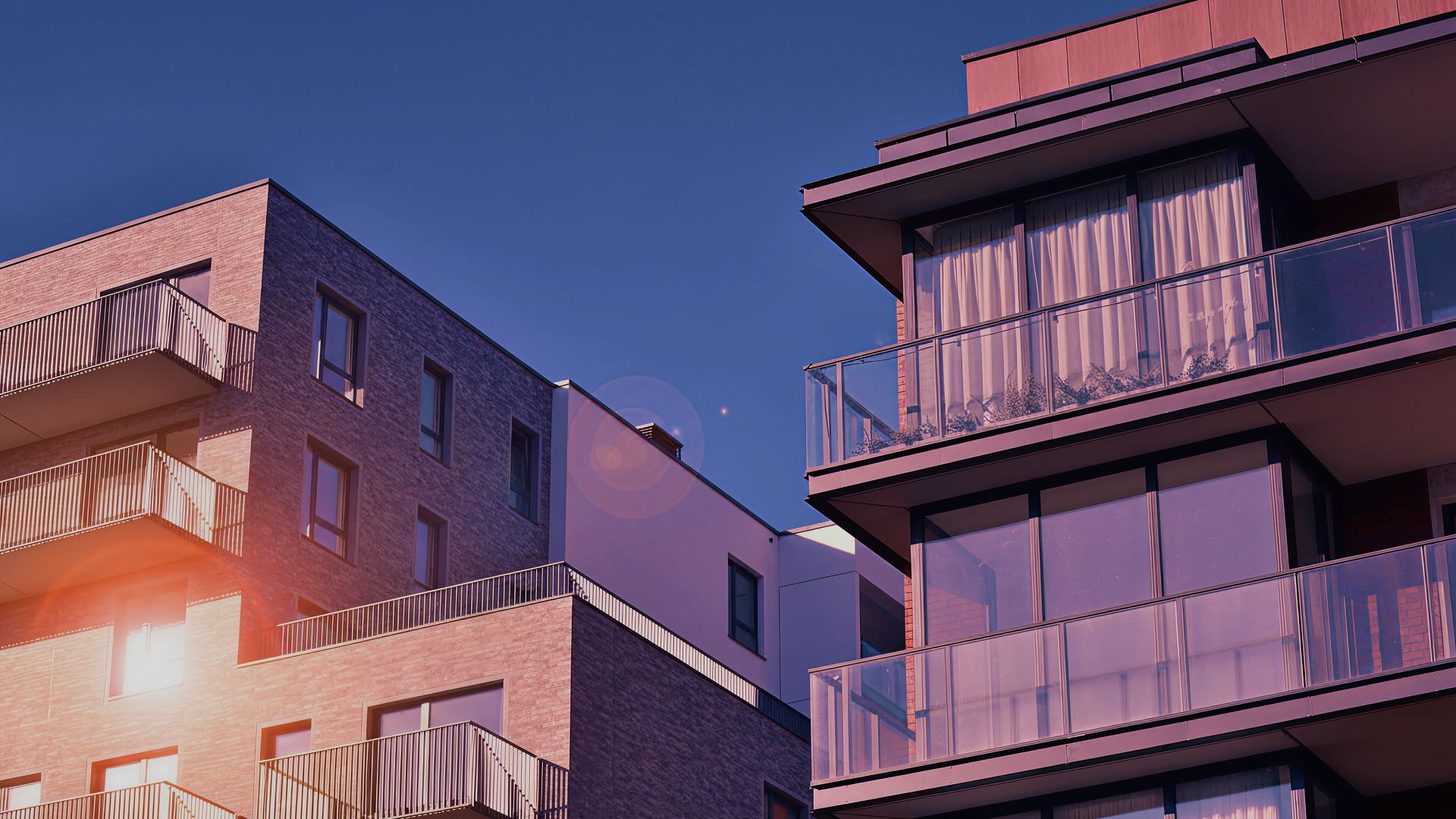 Modern residential apartment buildings at dusk with warm sunset light on the facades