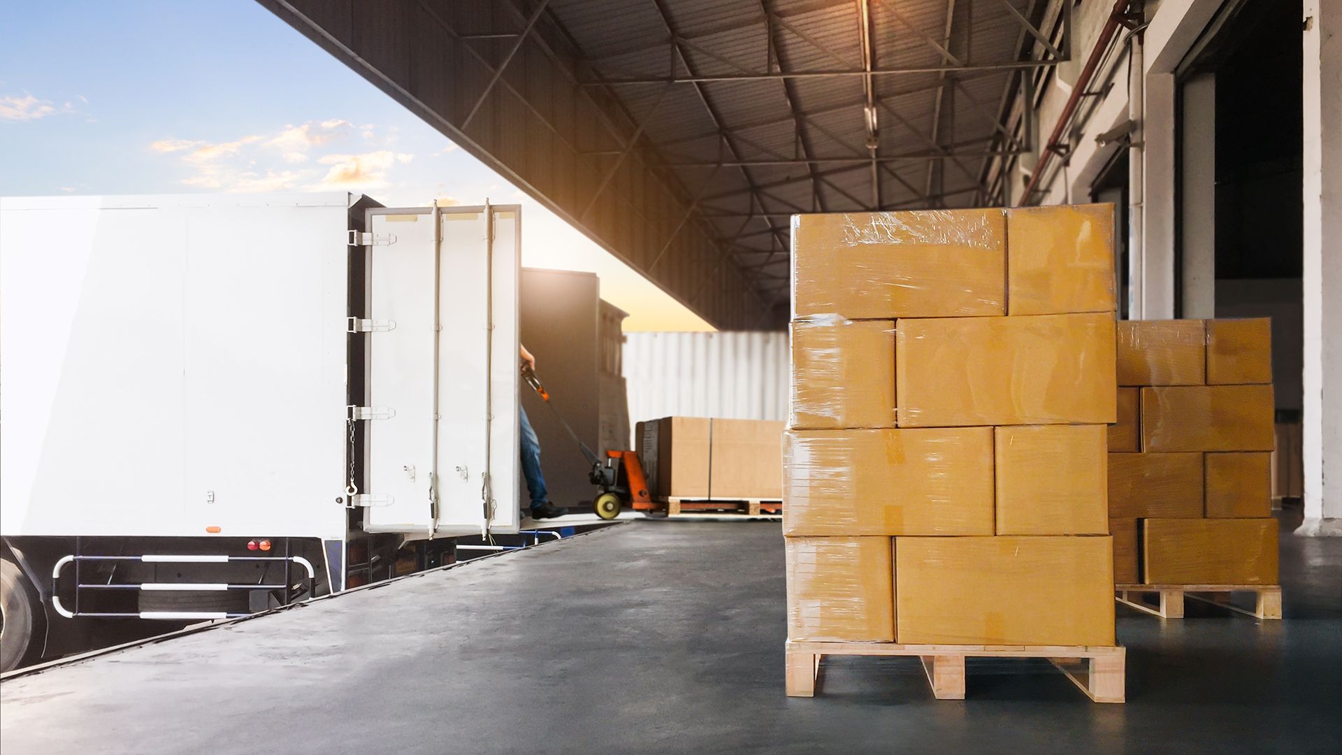 Warehouse loading dock with truck and stacked cardboard boxes ready for courier shipment