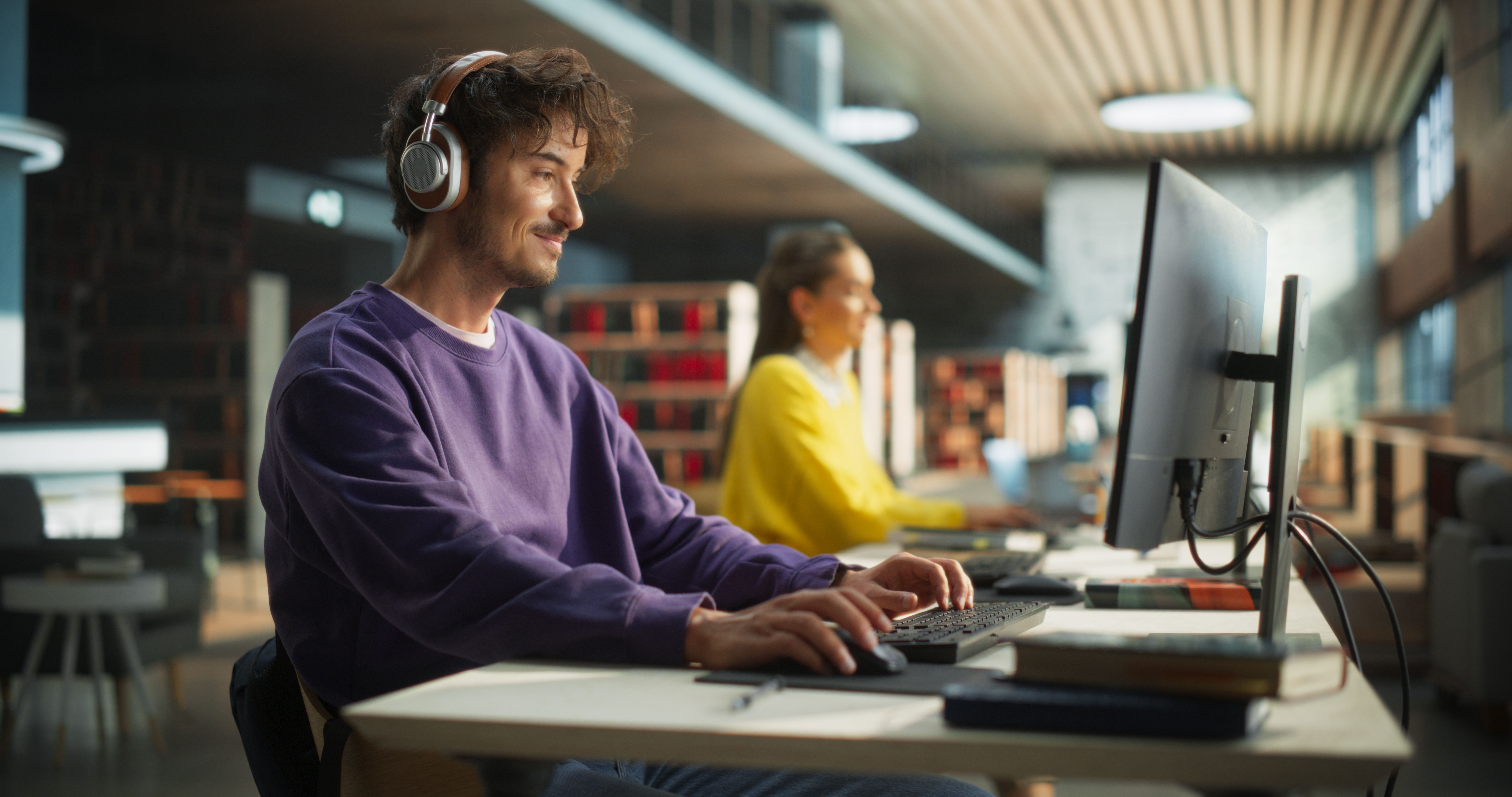 Developer with headphones working at a computer in a modern co-working space