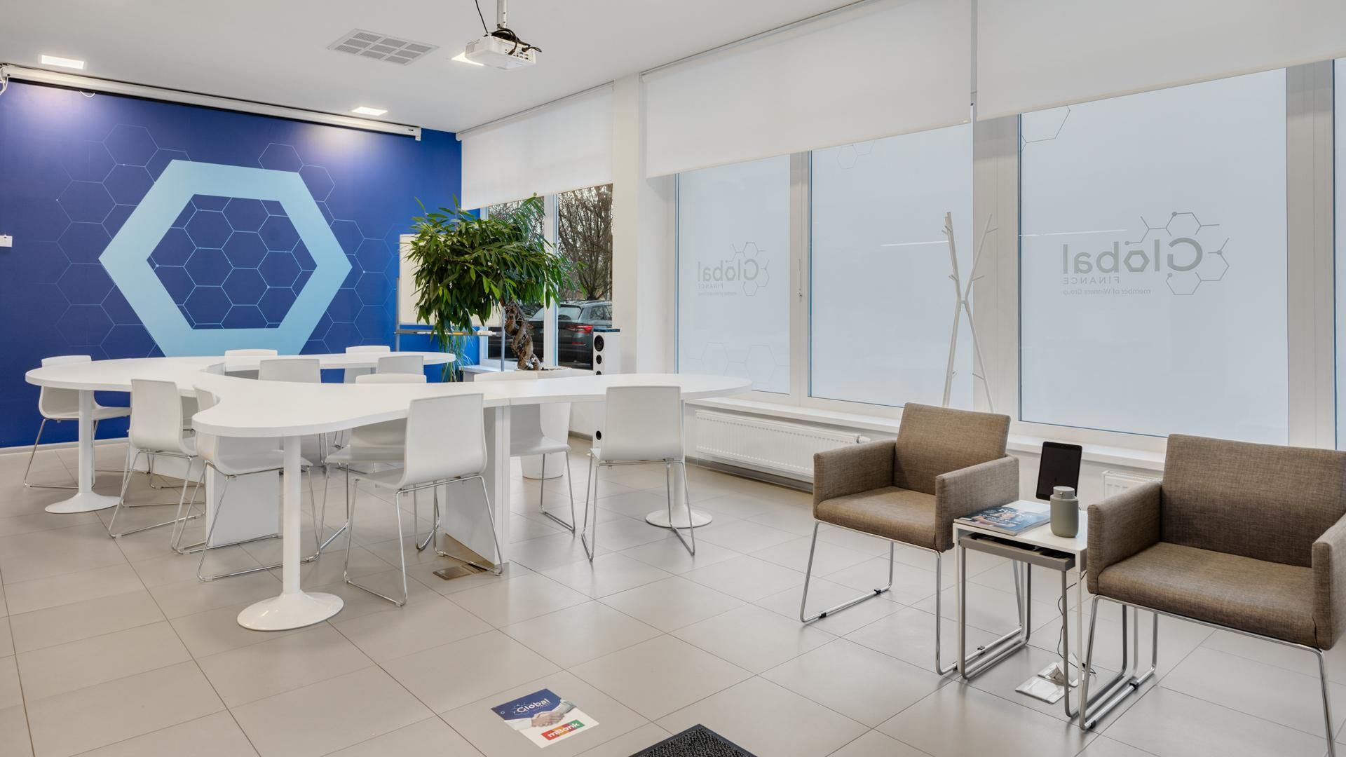 Global Finance branch interior with the company's hexagon logo on a blue wall, meeting tables and a lounge area